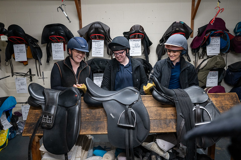 three students adjusting saddles