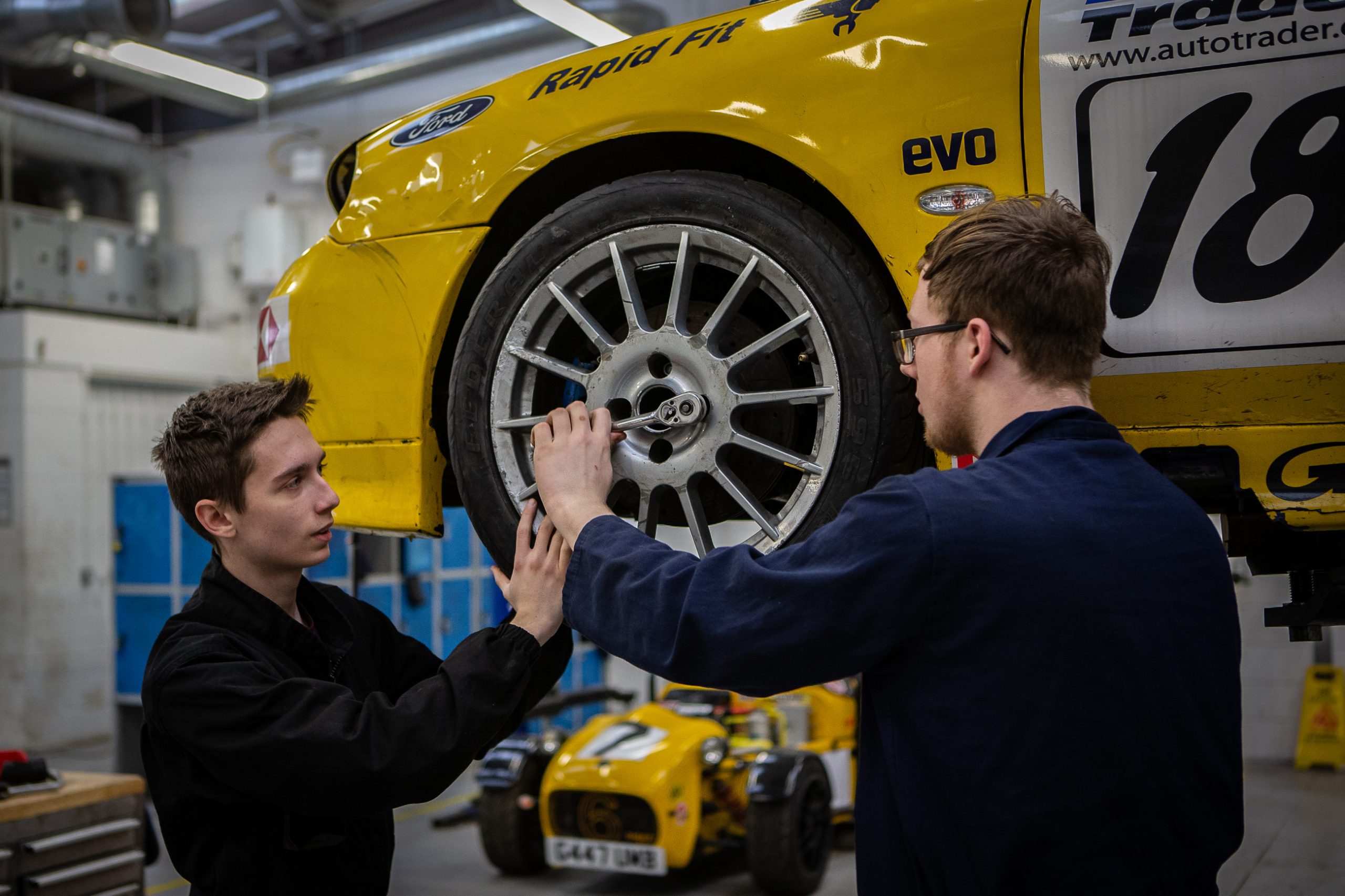 Two students attaching a wheel to an elevated car