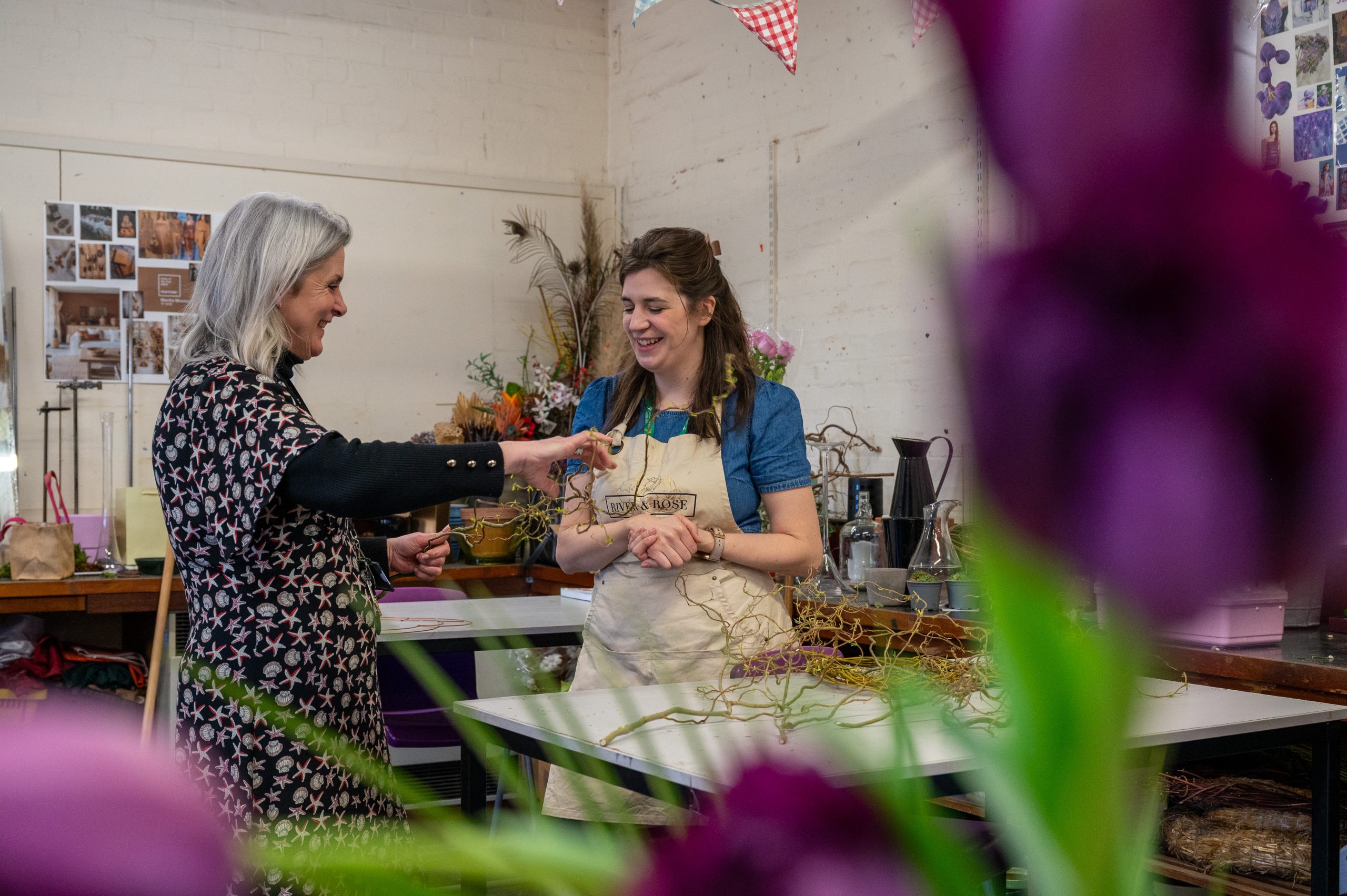 Image of floristry student and staff adjusting flowers