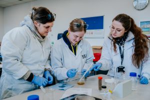 Three people in lab coats doing an experiment