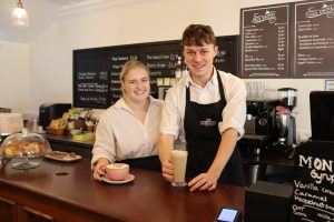 Two baristas holding coffees.