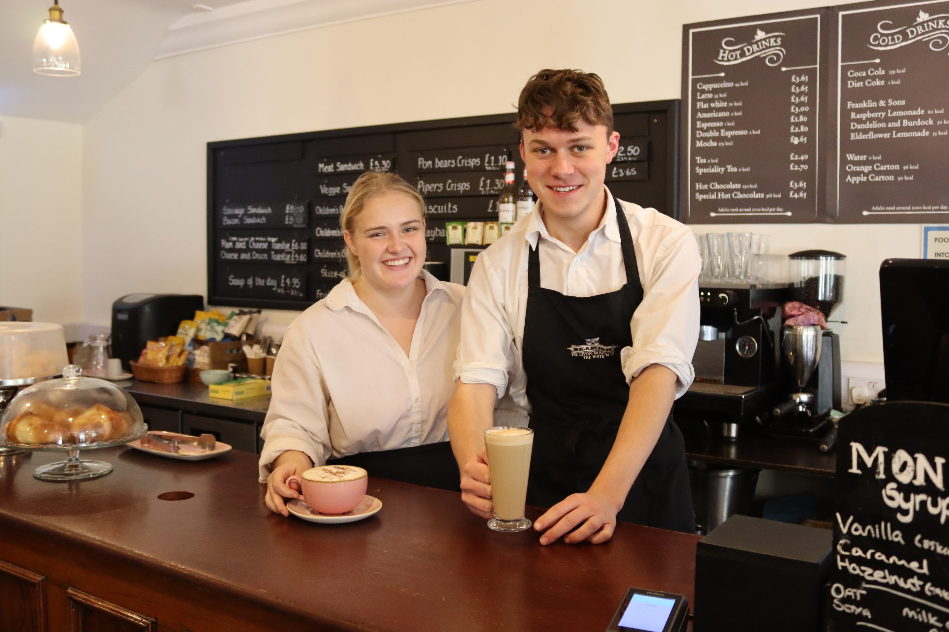 Two baristas holding coffees.