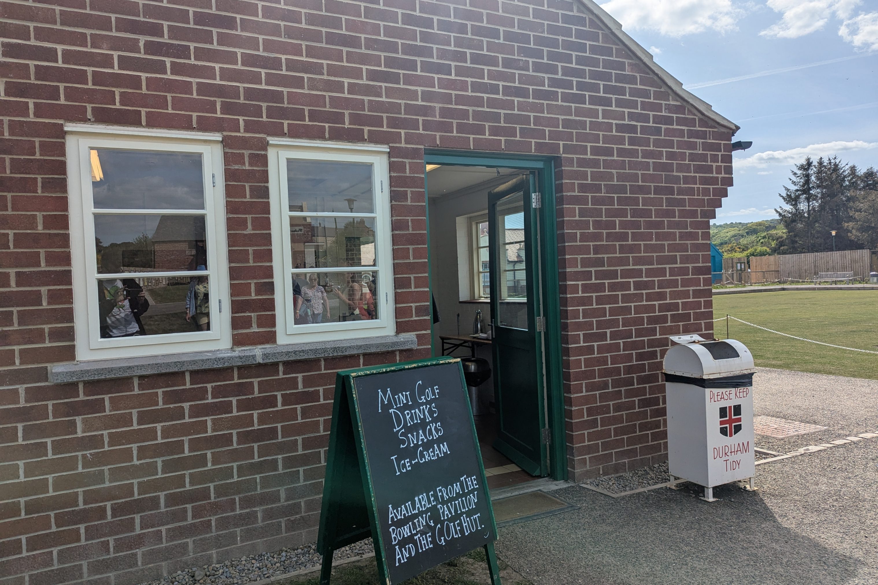 Mini gold signage outside brick building bowling pavilion.