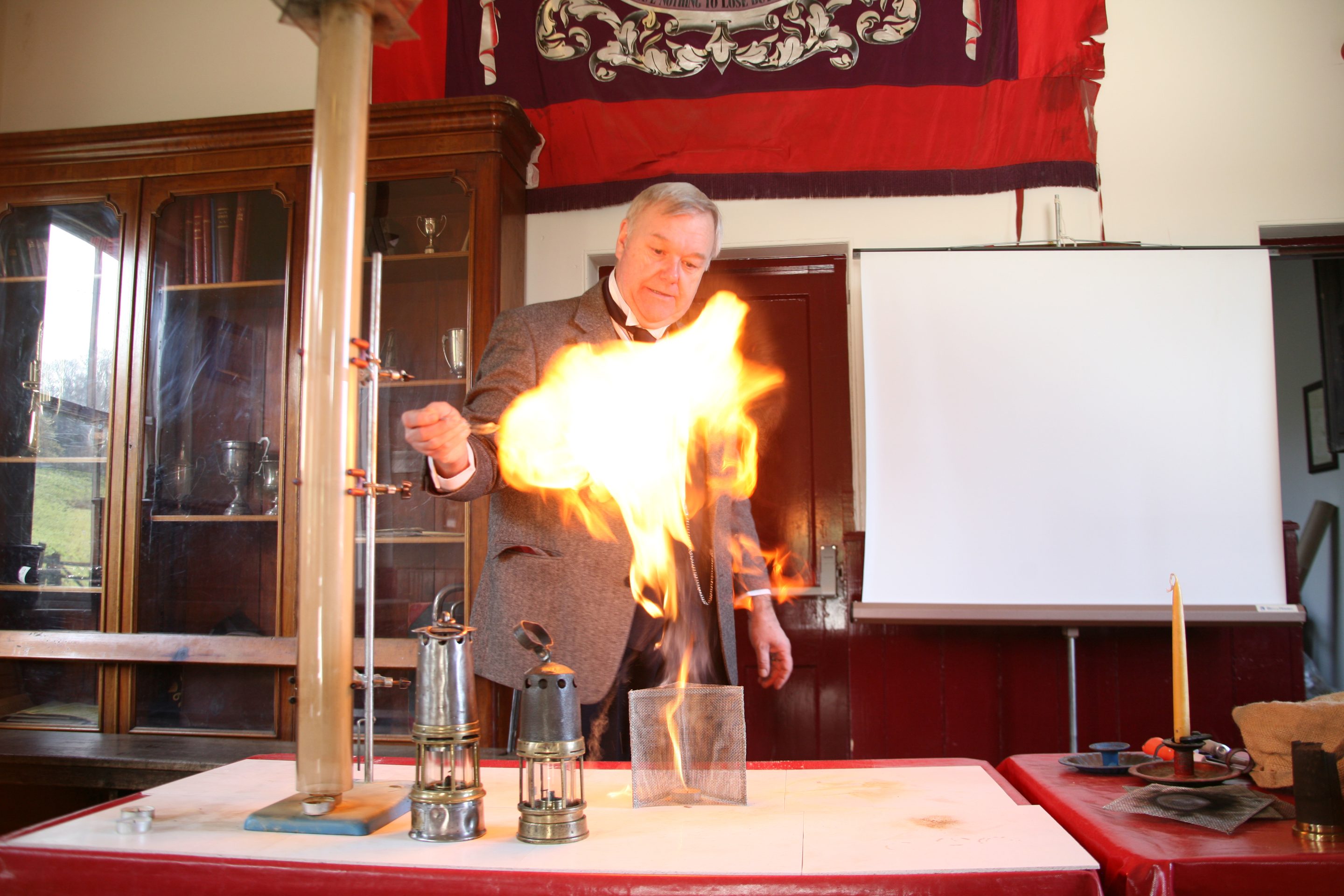 Figure with controlled fire explosion above bunson burner.