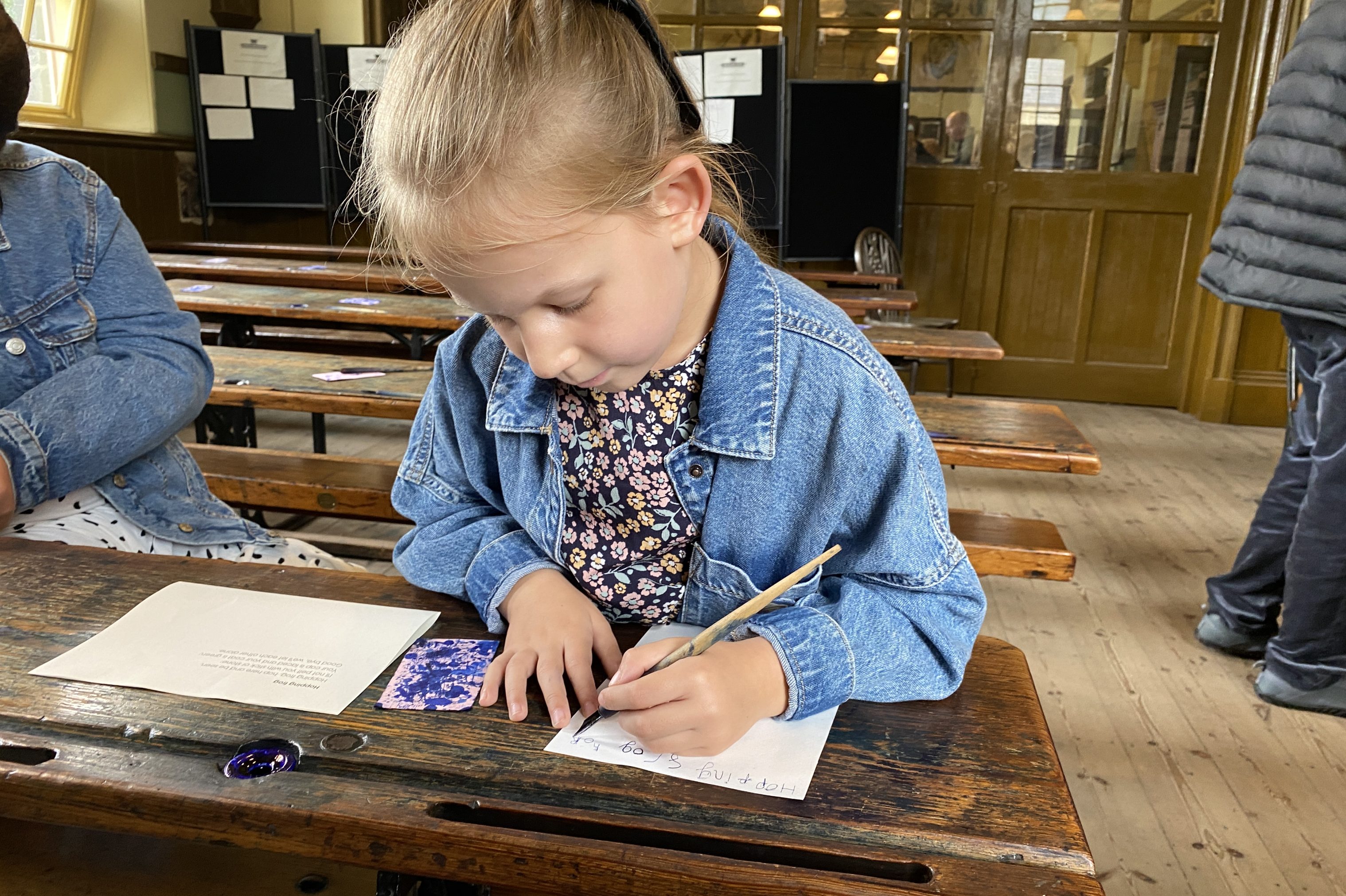 Young person dipping pen into ink.