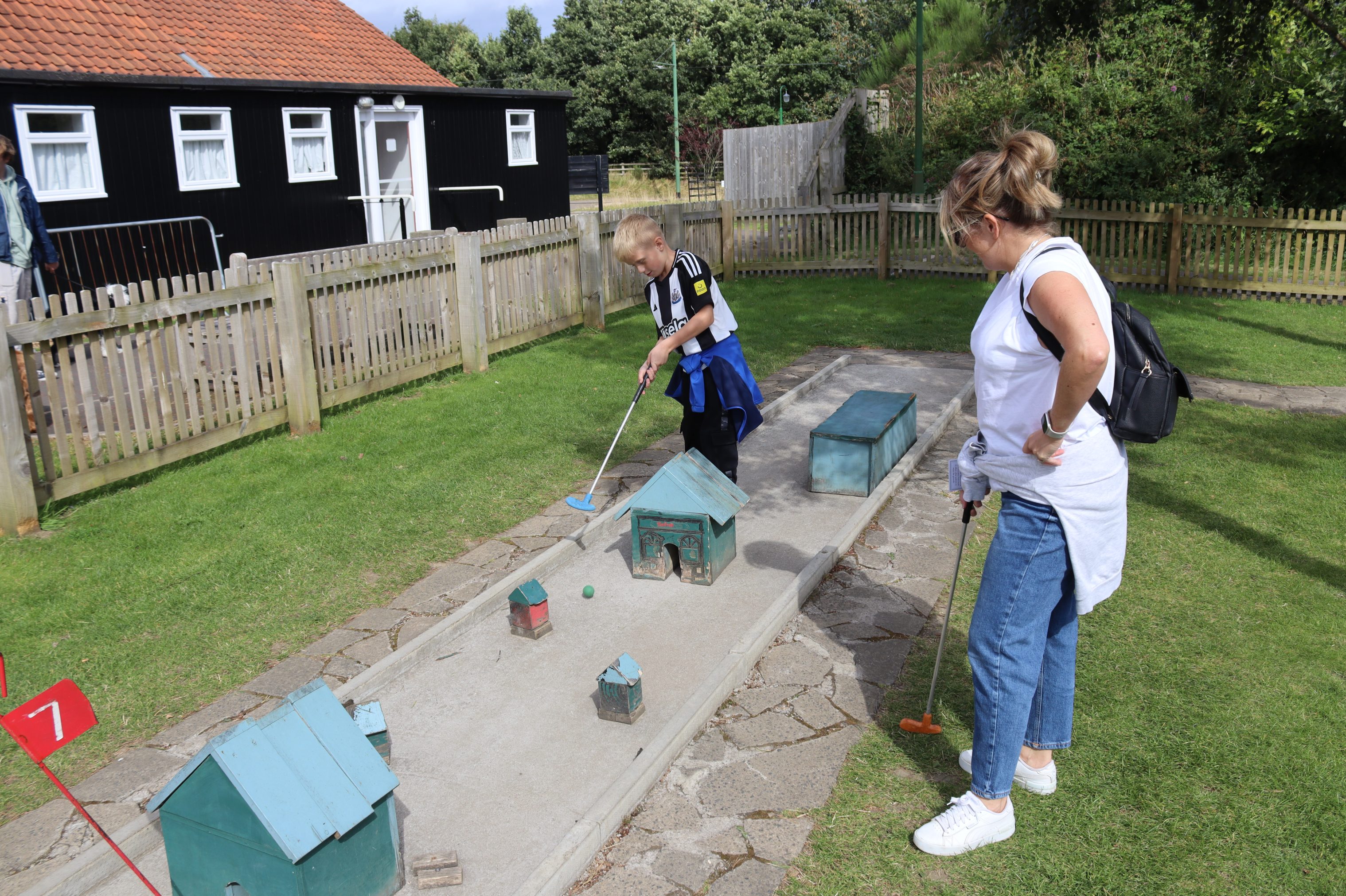 Adult and child playing mini golf.