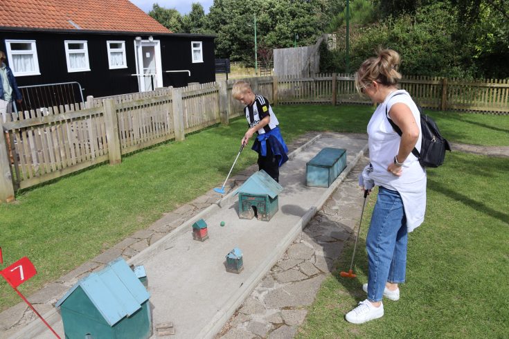 Adult and child playing mini golf.