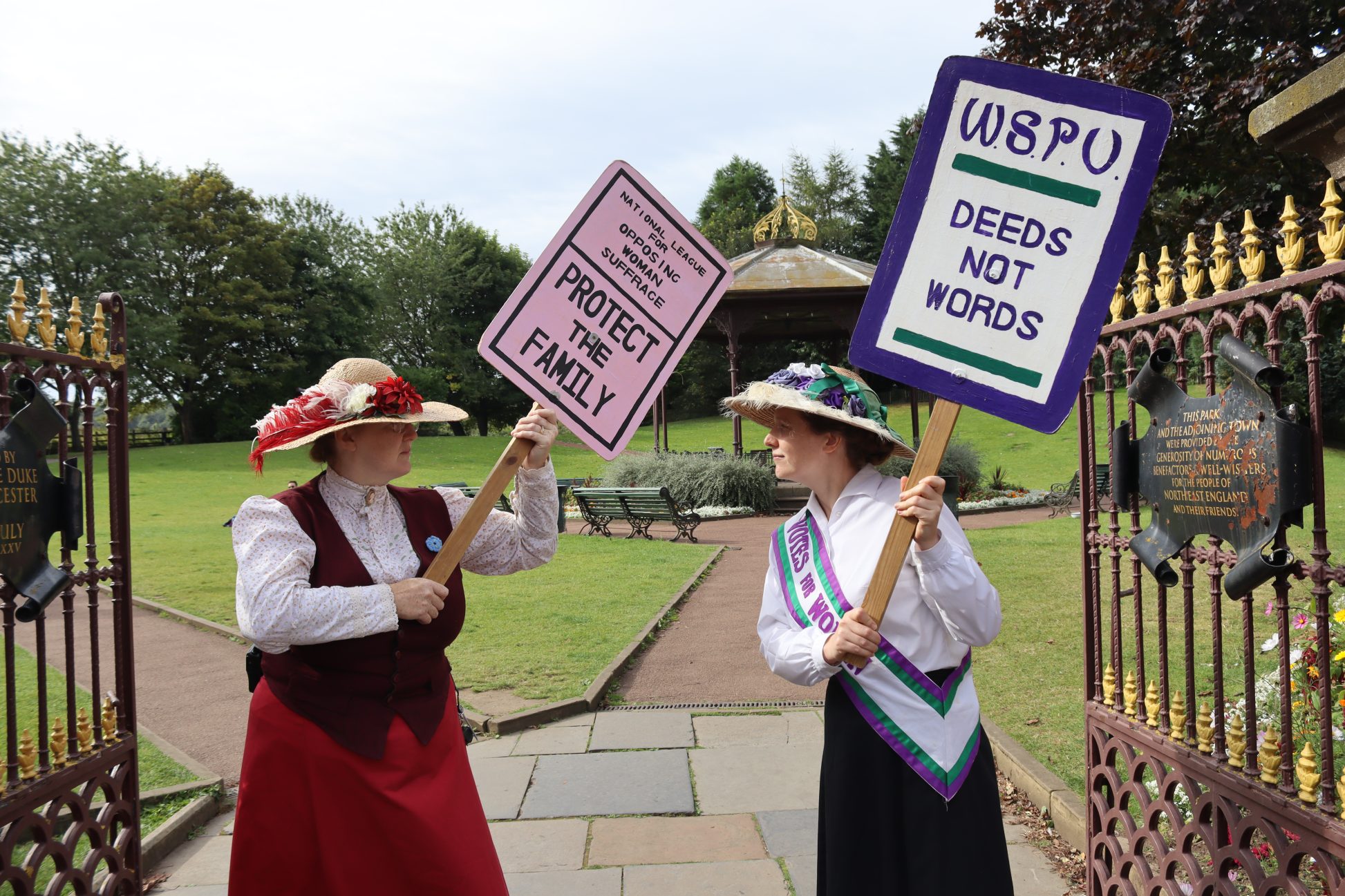 Two staff members dressed in Edwardian costume, with messages opposing and for women's suffrage.
