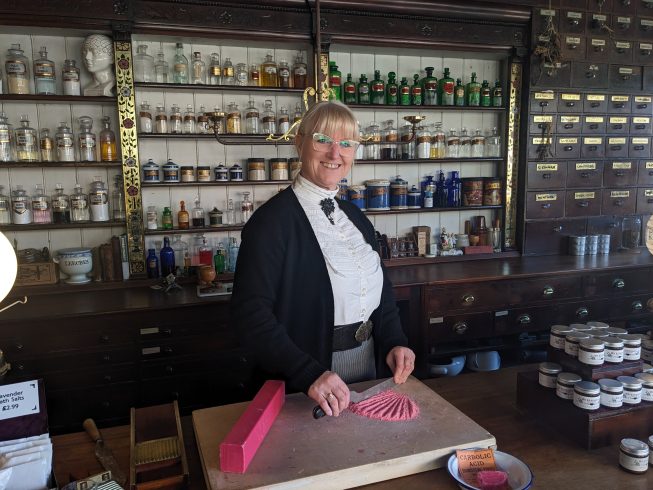Costumed staff member chopping carbolic soap.