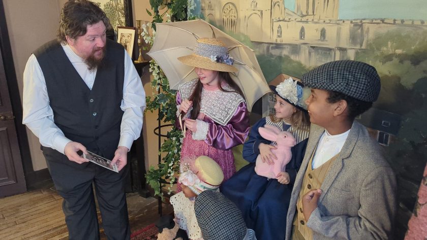 Costumed staff member talking to children in costume.