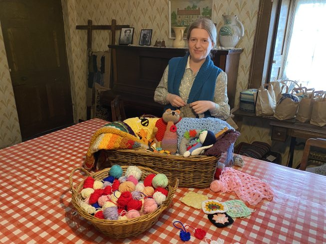 Staff member with array of knitted items.