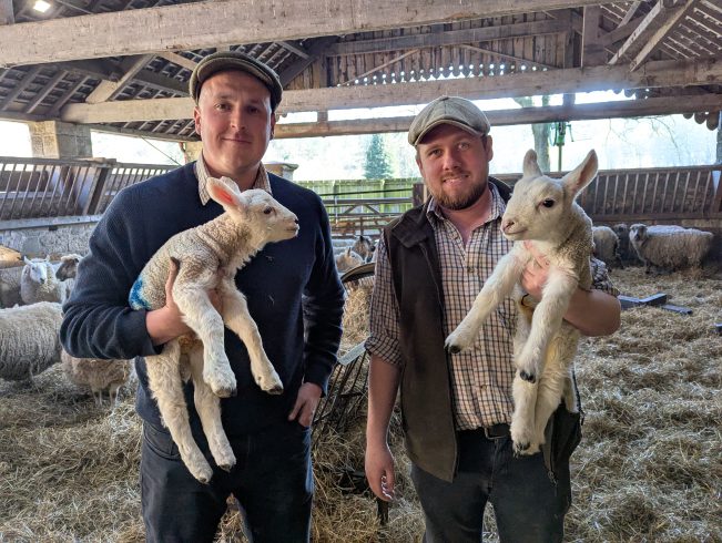 Two staff members holding lambs.