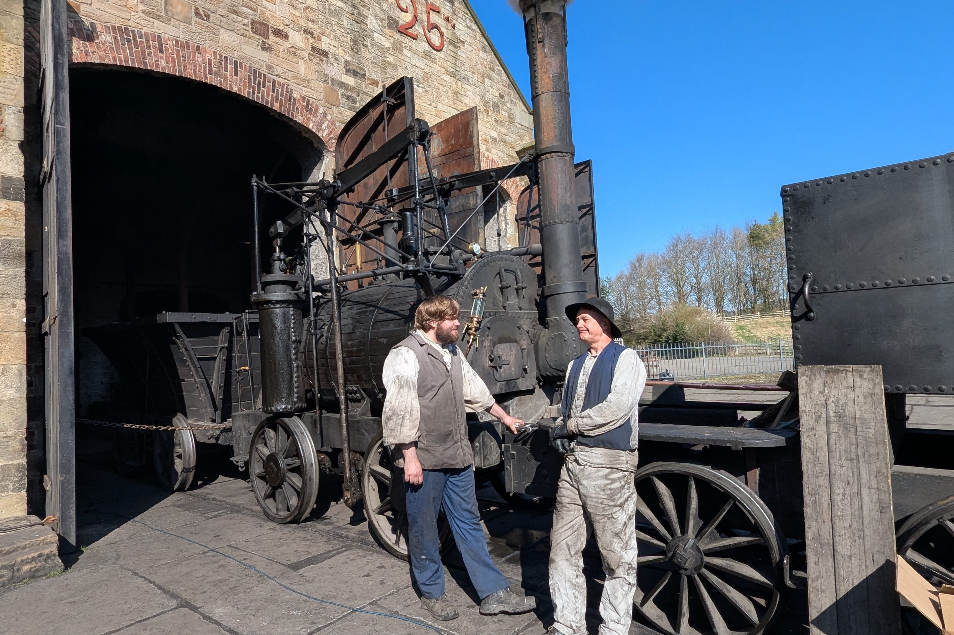 Two staff members stood in front of Georgian steam locomotive.