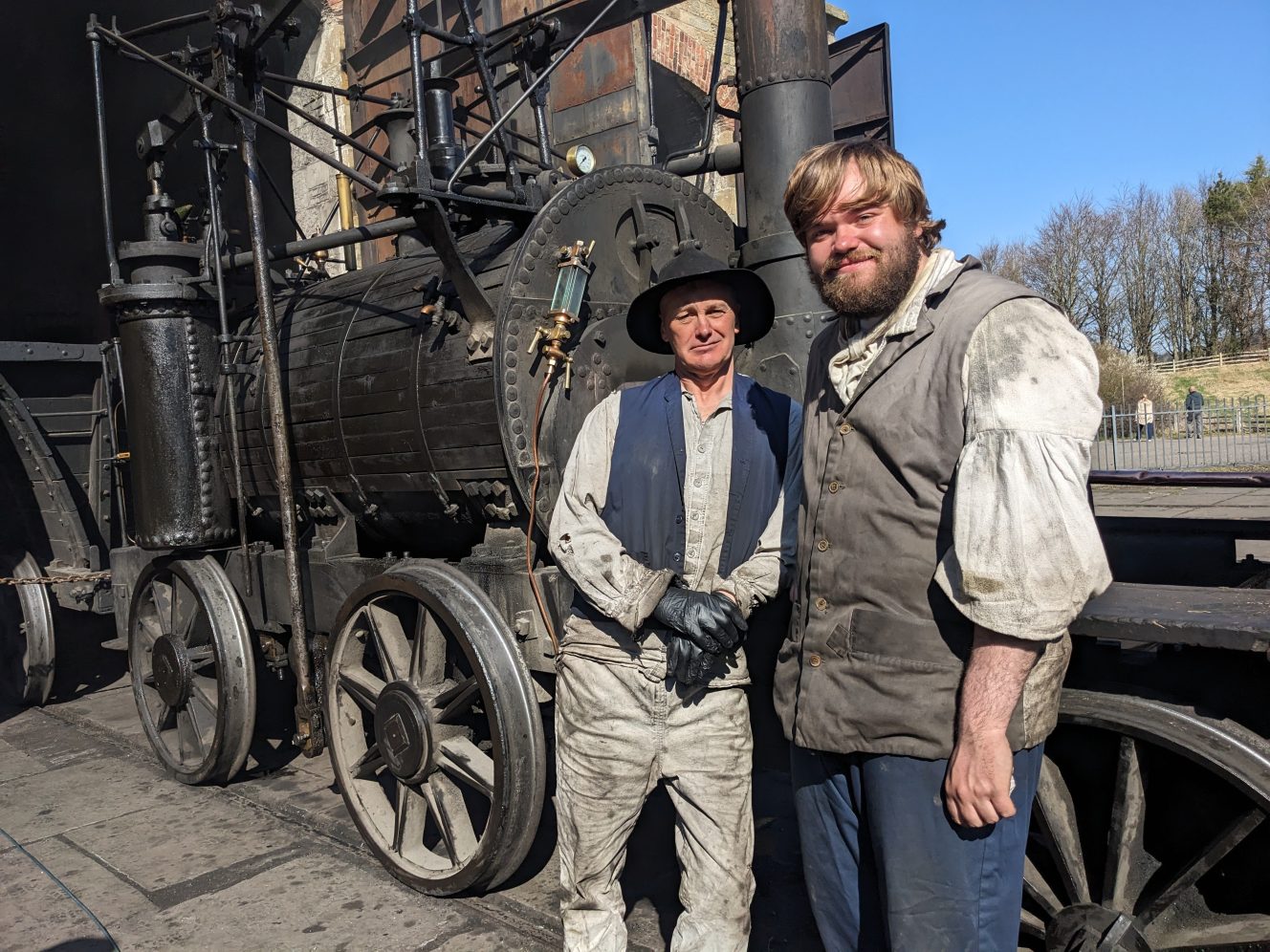 Two staff members stood in front of Georgian steam locomotive.