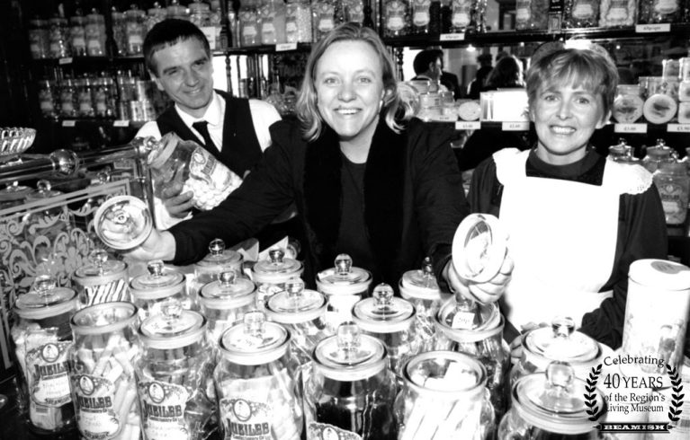 MP stood in the middle of two staff members, with multiple jars of sweets surrounding them.