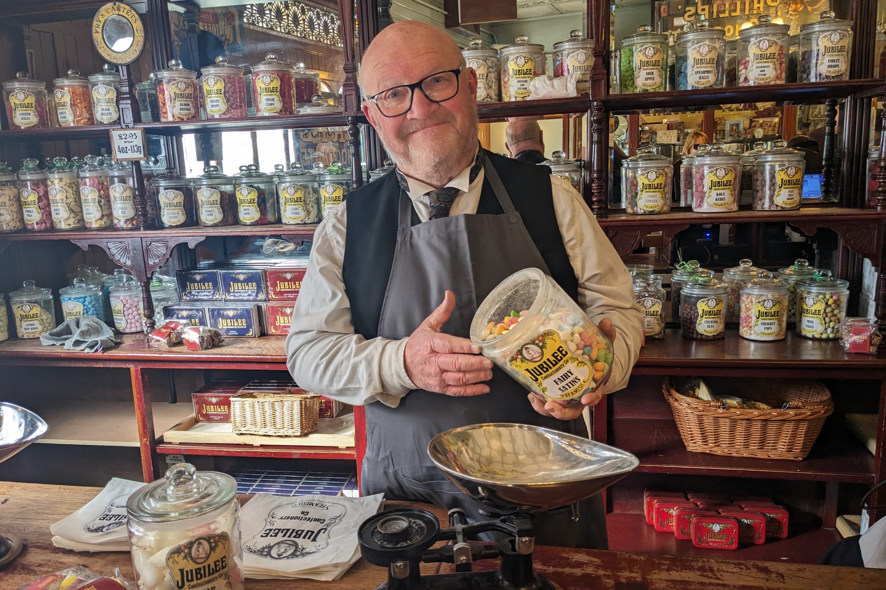 Costumed staff member pouring jar of sweets.