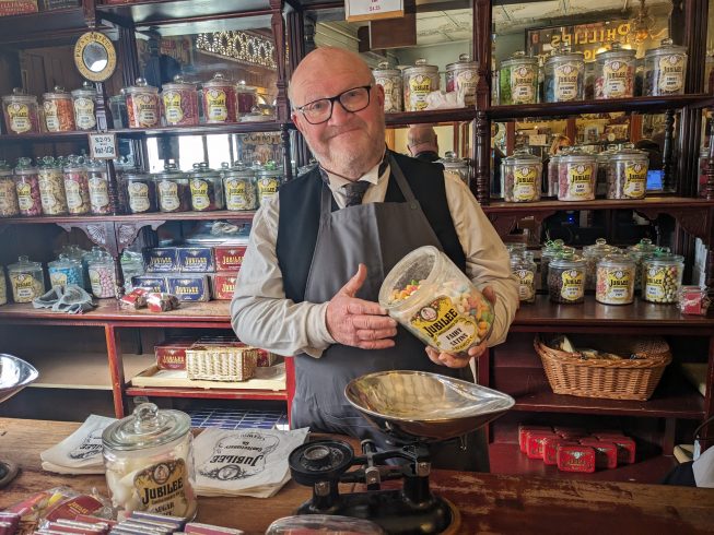 Costumed staff member pouring jar of sweets.