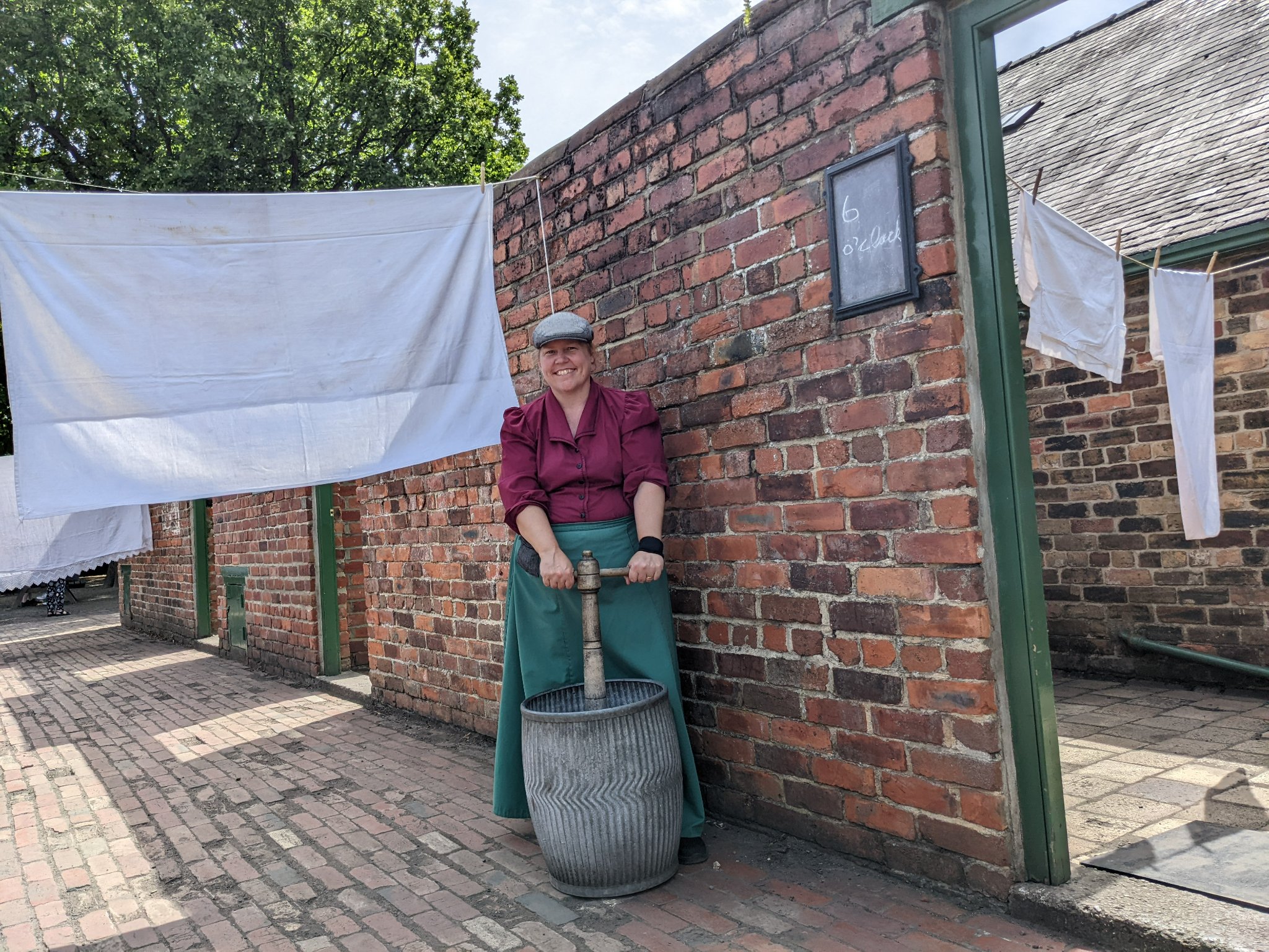 A person doing washing with a poss tub