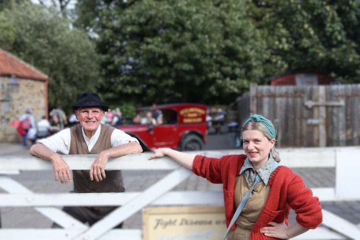 Two people learning on a white fence