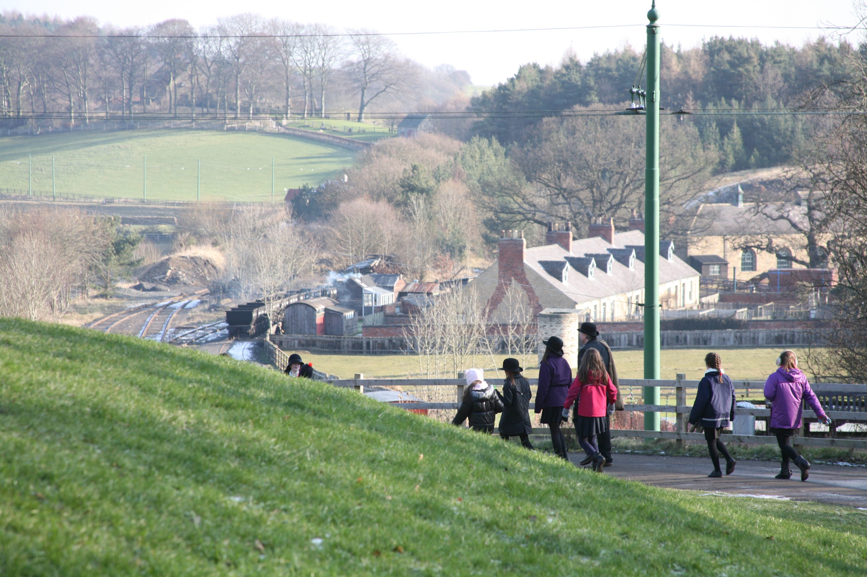 Young people walking with Pit Village in the distance.