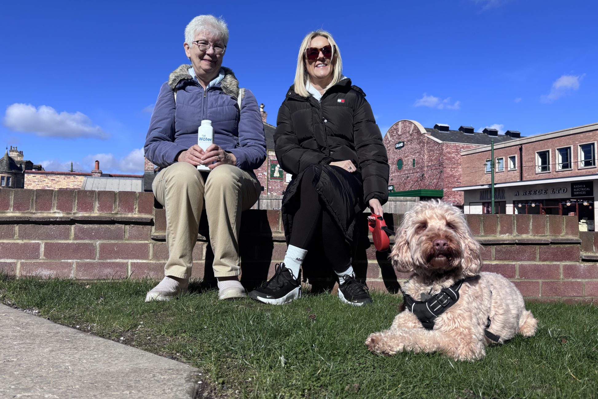 Two visitors sitting on a wall, with dog