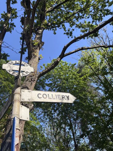 Signage for the colliery amongst a blue sky and trees