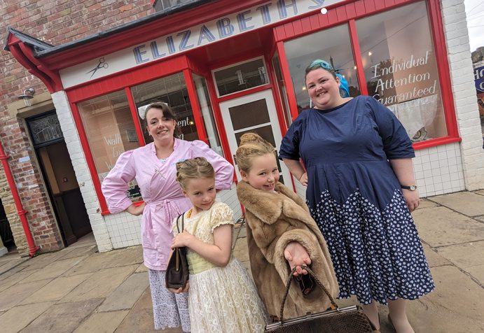 Two young visitors with two staff members posing outside of Elizabeth's hairdressers.