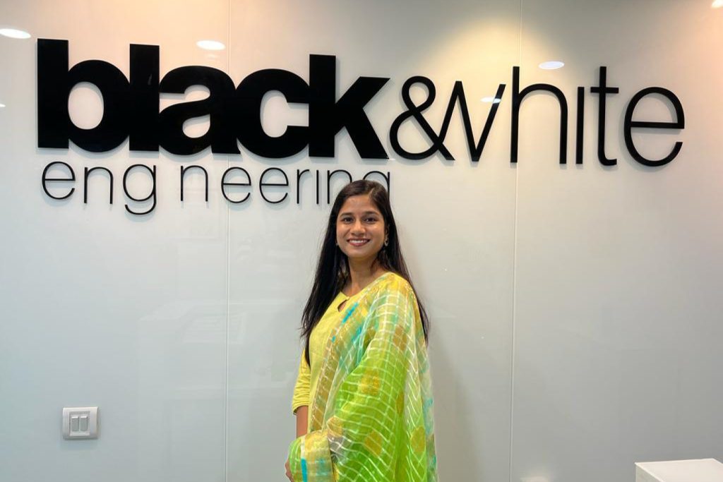 Shivani Jain Electrical Engineer in front of the Black & White Engineering signage wearing traditional Indian dress.
