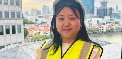 Electrical Engineer Wai Mon Theint wearing PPE standing in front of buildings in Singapore.