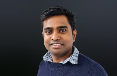Head shot of Ram Sethuramaglingam smiling against a dark grey background.