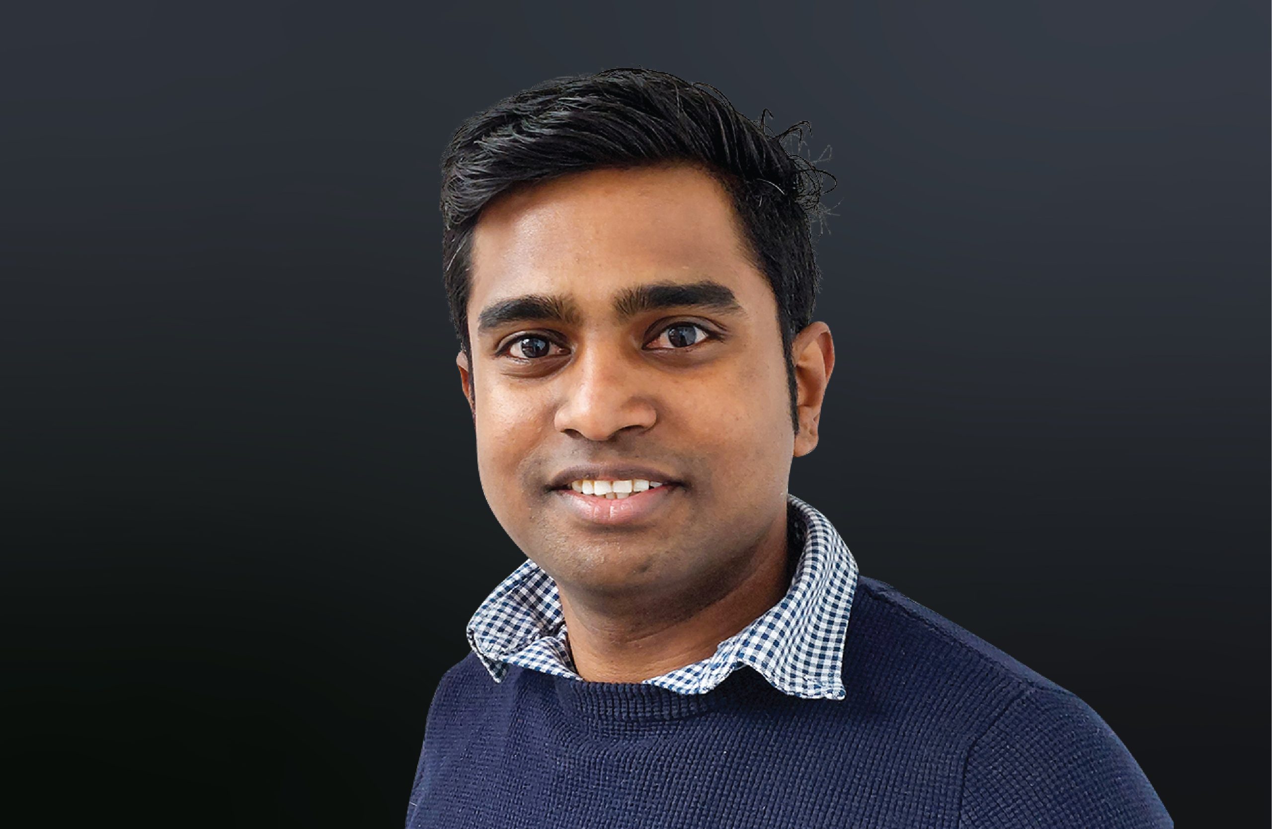 Head shot of Ram Sethuramaglingam smiling against a dark grey background.