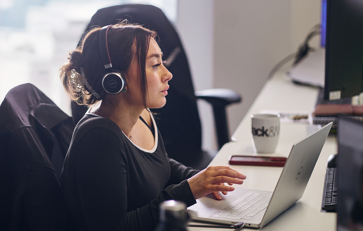 A female intern wearing a headset working at her desk