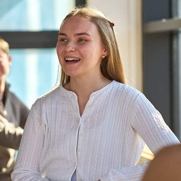 Cat smiling in a group team meeting wearing a white jumper.