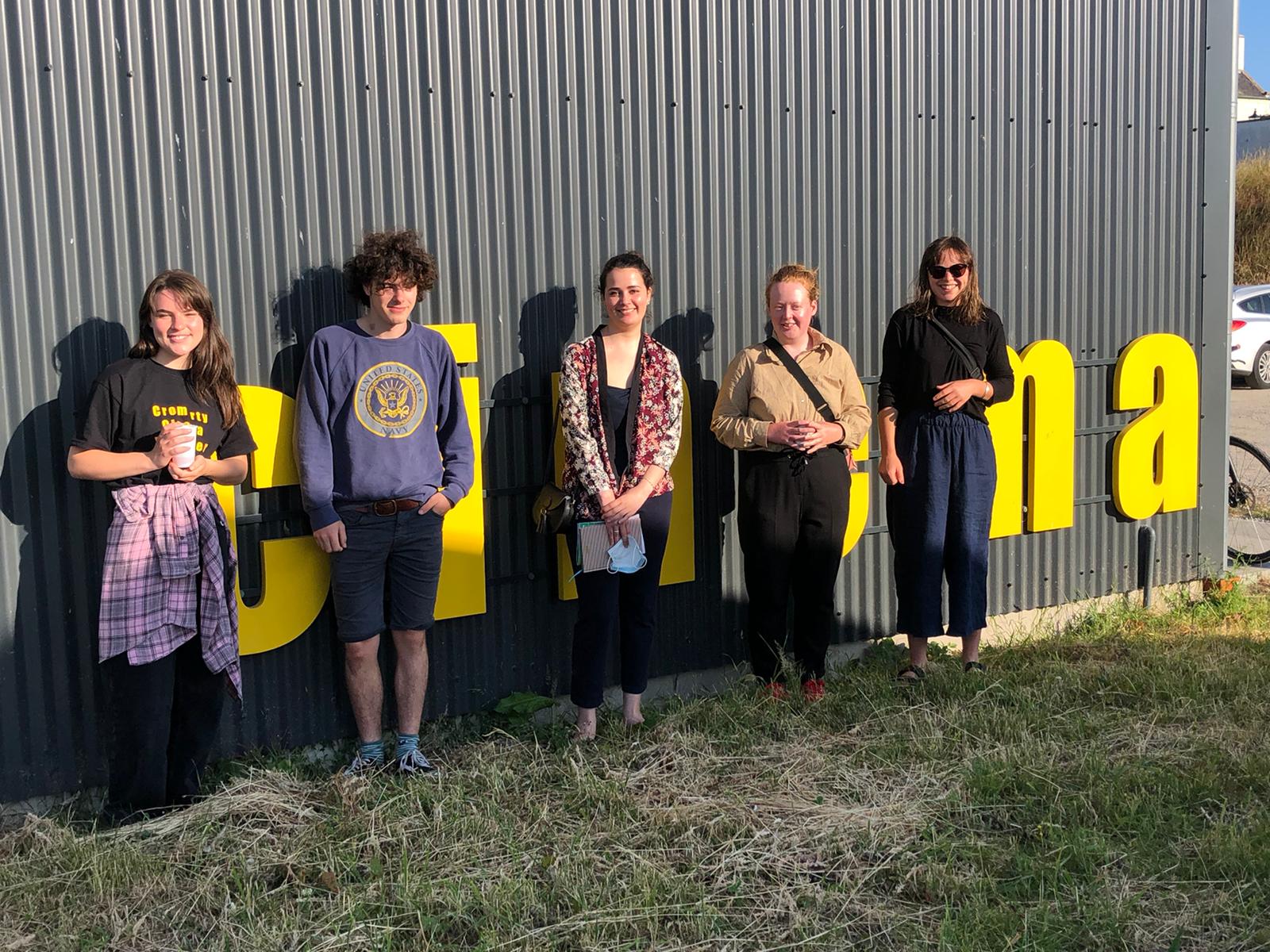 The Cromarty young programmers group stand in front of a building, with cinema written on the side in big yellow letters.