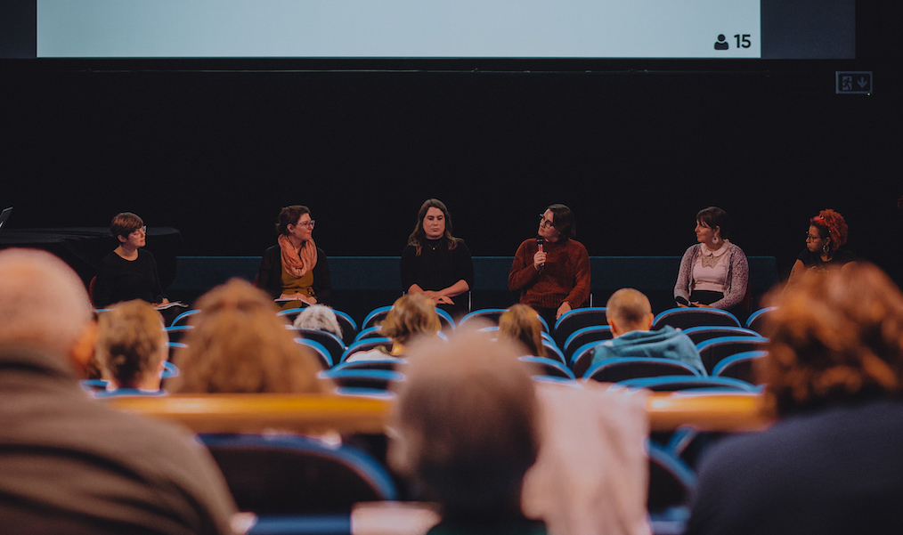 A cinema audience watches a panel on stage