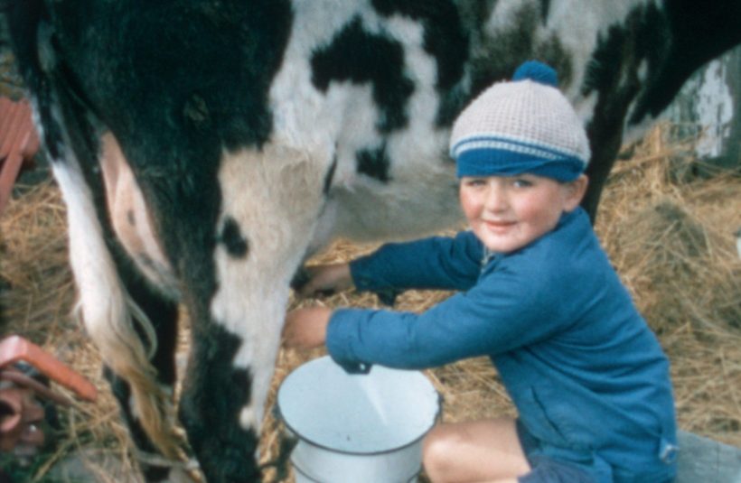 Duthchas still. A young boy milks a cow.