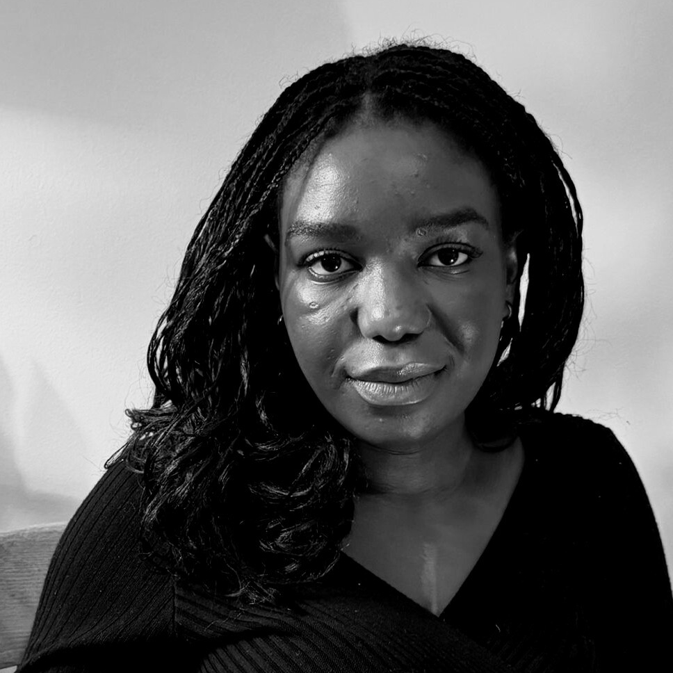 Black-and-white headshot of Balenji Mwiche looking at the camera, with long braided hair and wearing a dark top.