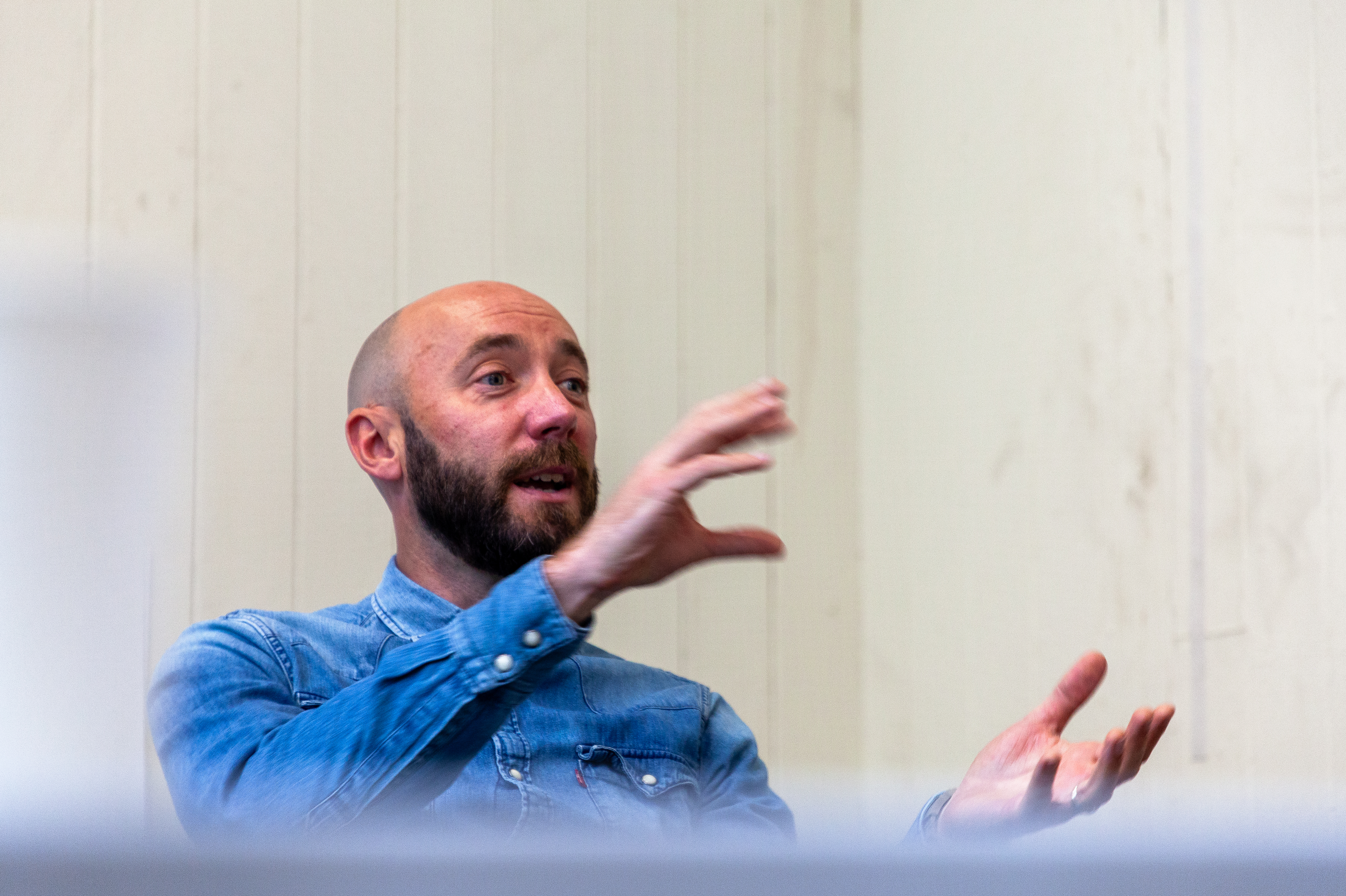 A man in a denim top talking.