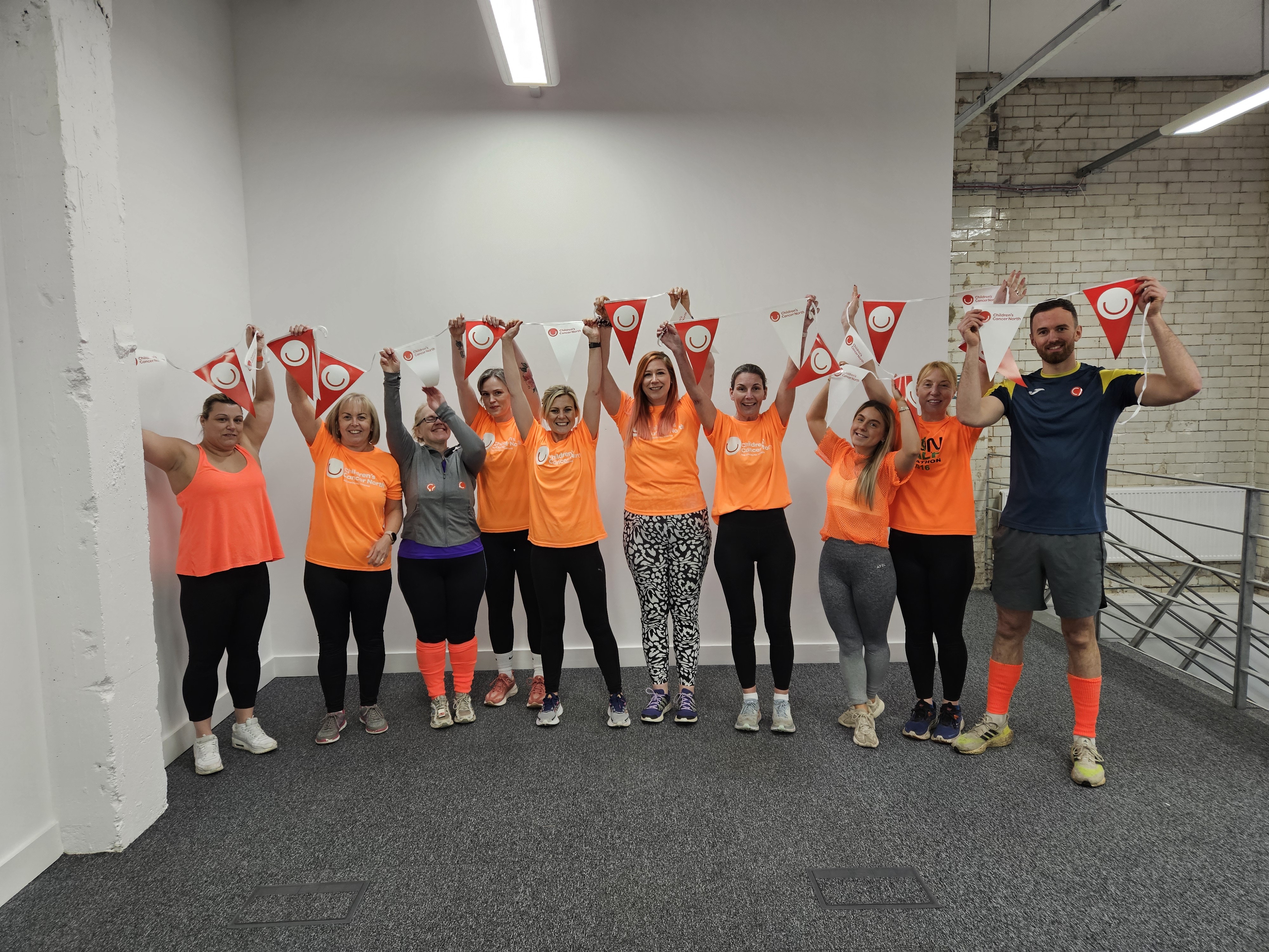 A group of people wearing orange holding up flags.