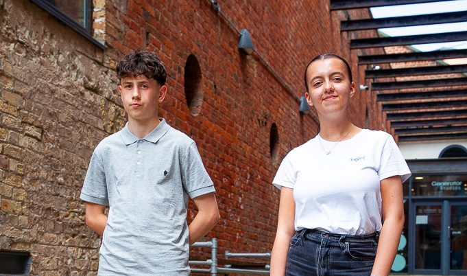 Two students smiling in a walkway