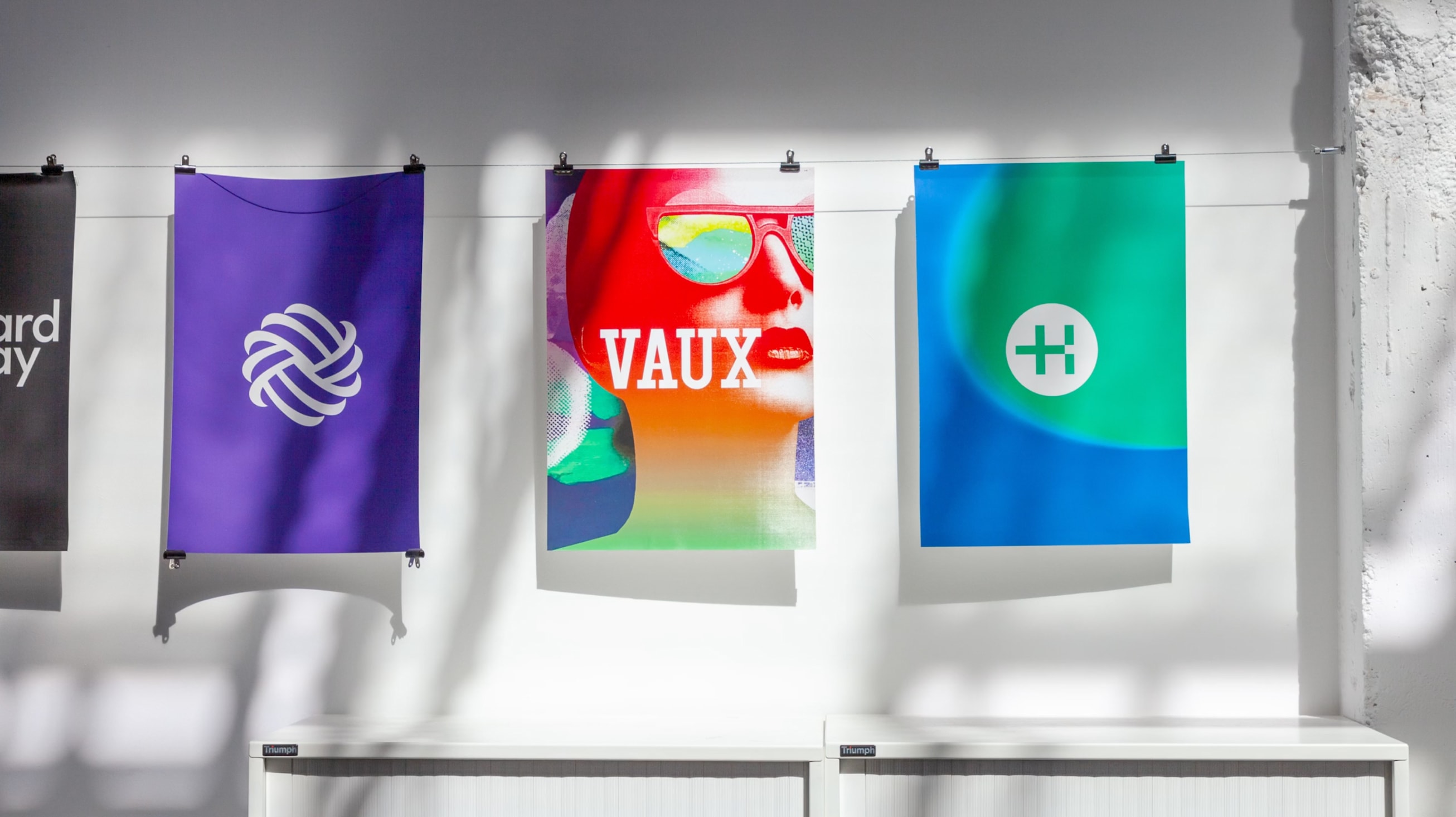 An image of colourful posters hanging from a white wall.