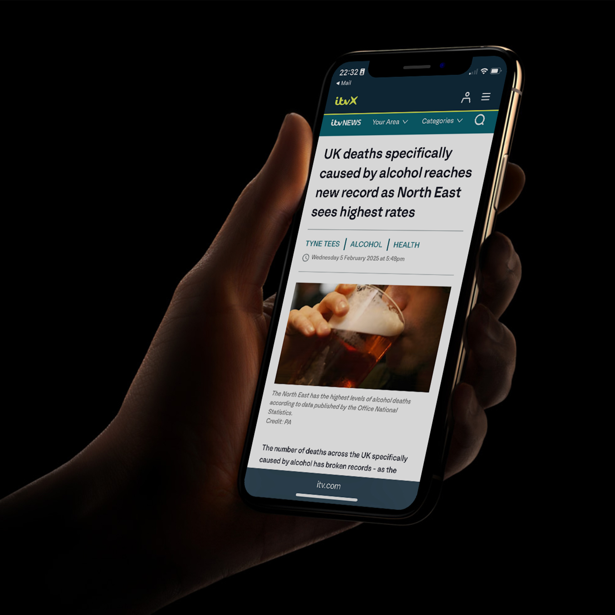 A hand holding a phone showing a news article