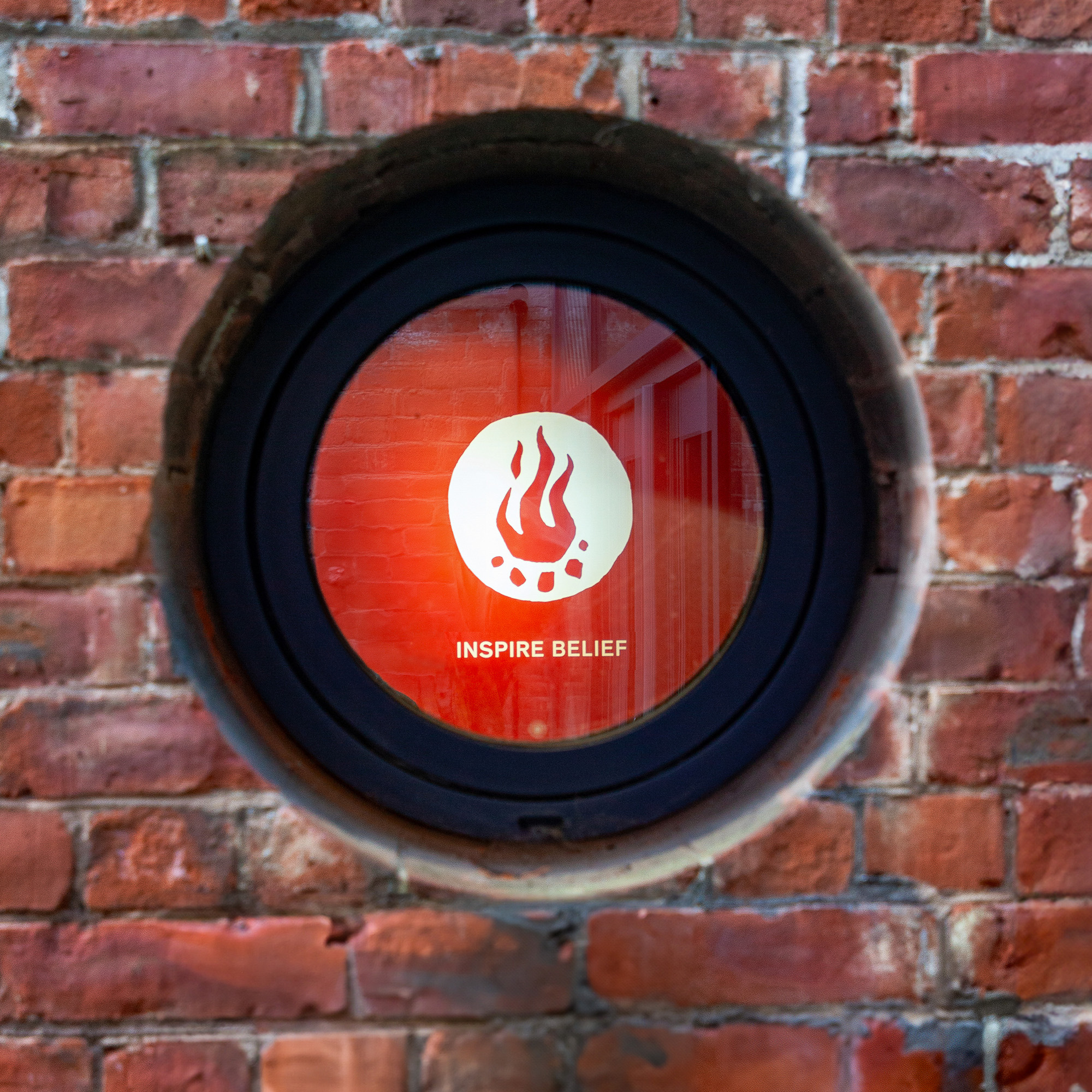 A window into a building that has a slogan on the wall saying Inspire Belief.