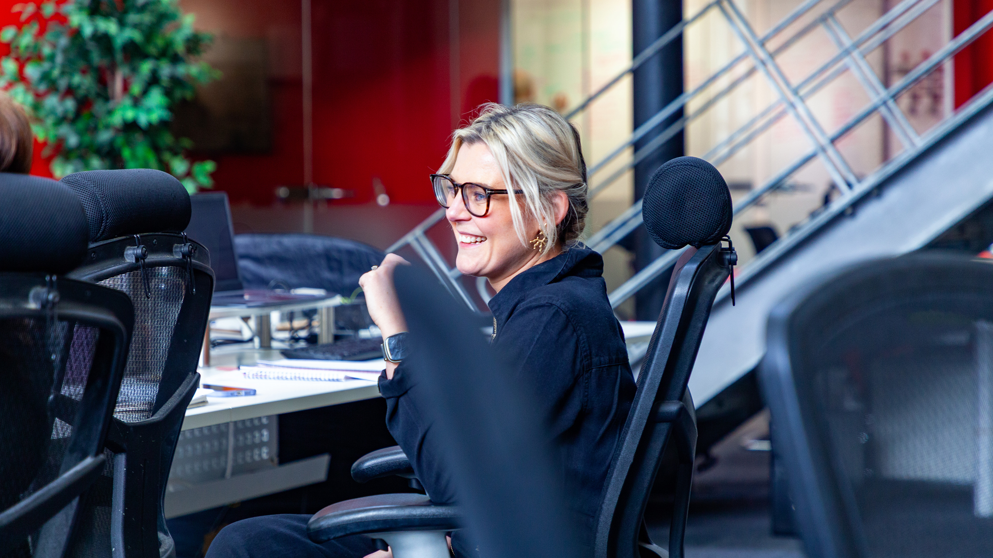 A blonde woman is sitting down and smiling.