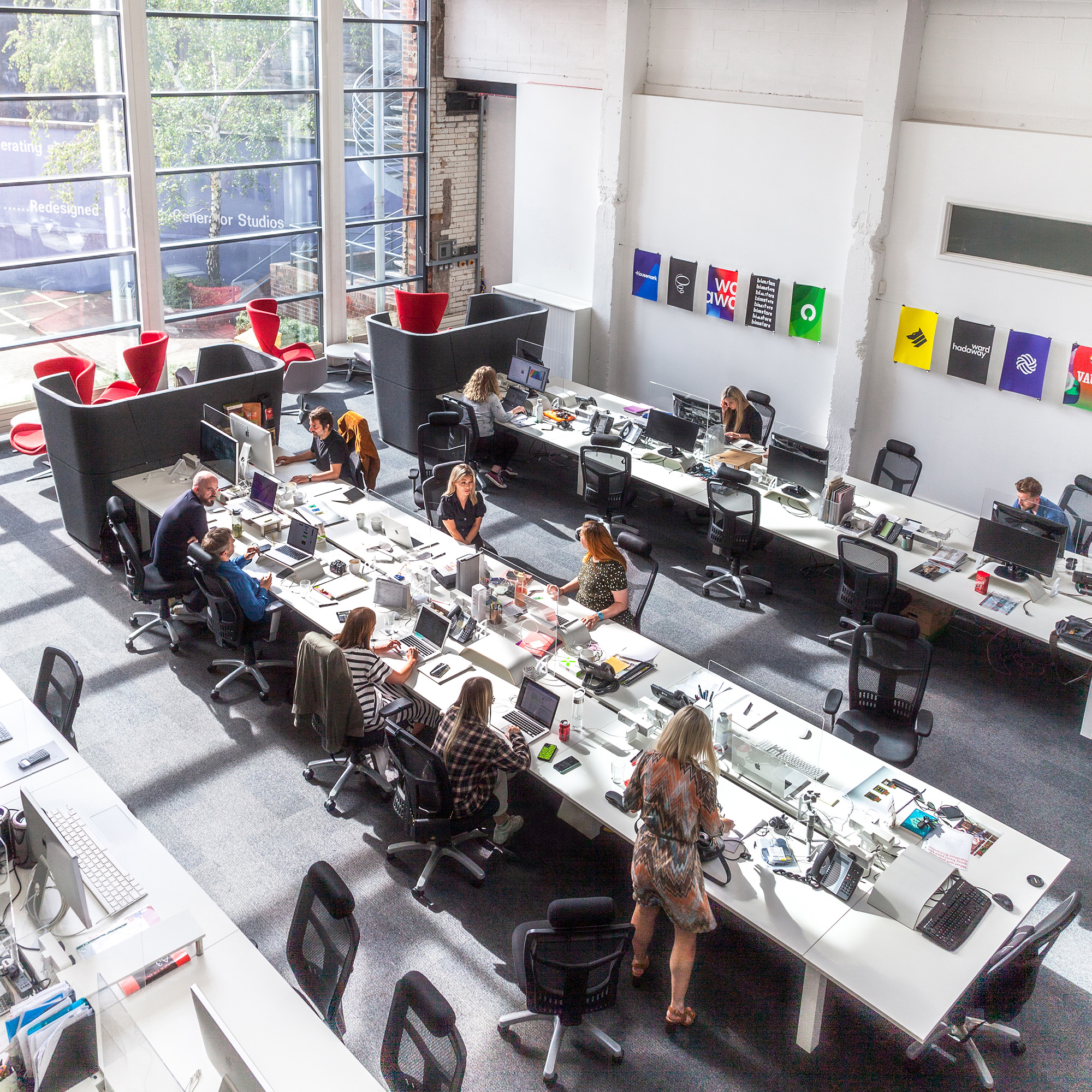 People work and interact with computers in bright office space.