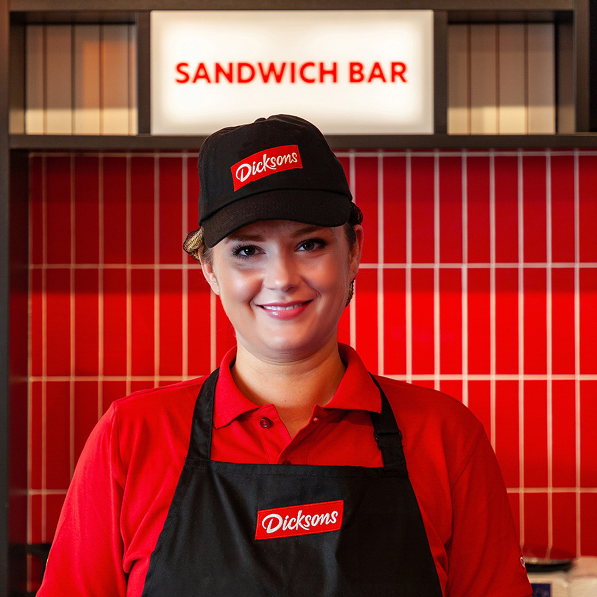 Person smiling wearing a cap and apron.