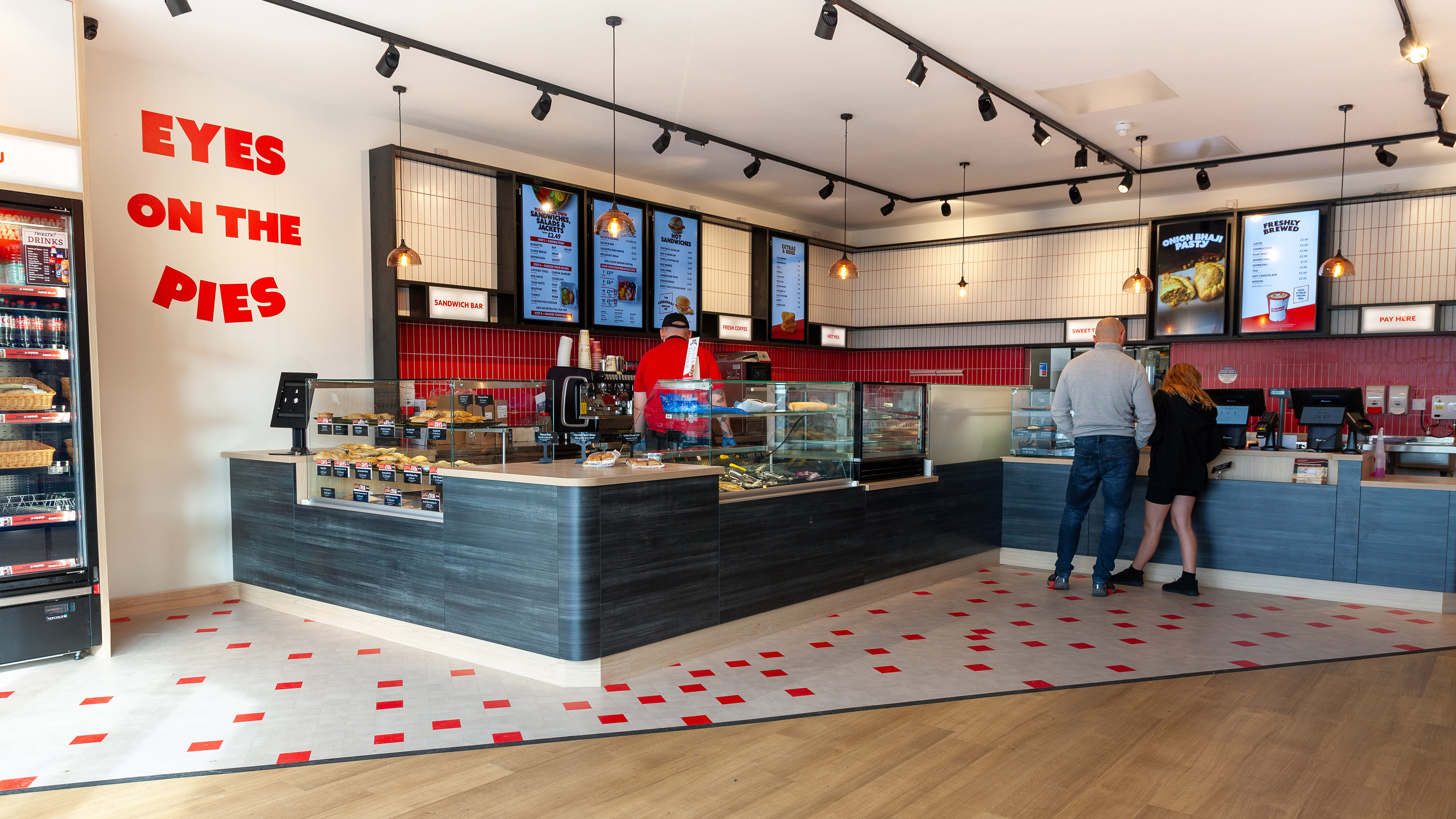 People ordering food at deli counter.