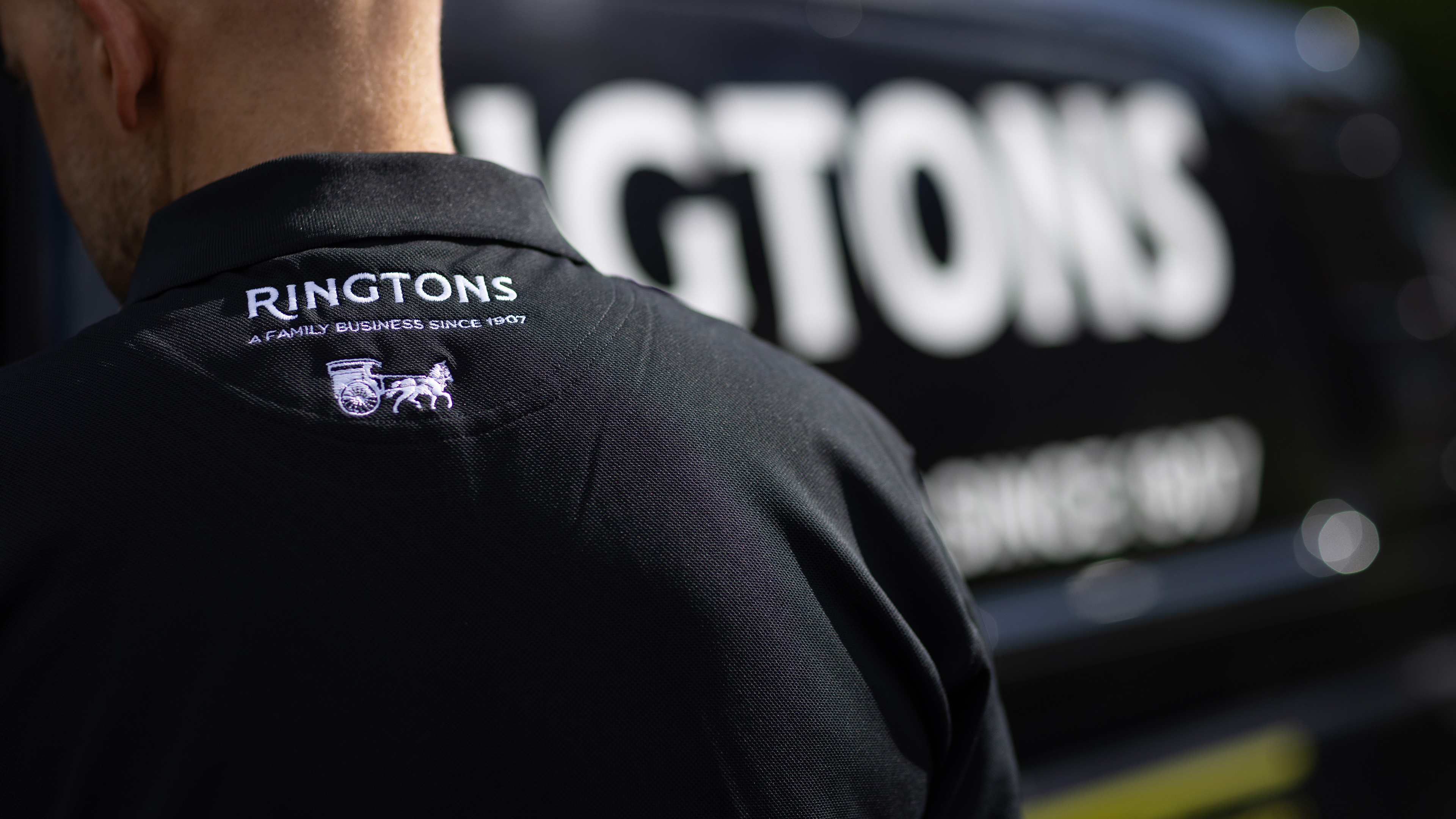 Person facing delivery van wearing black t-shirt.