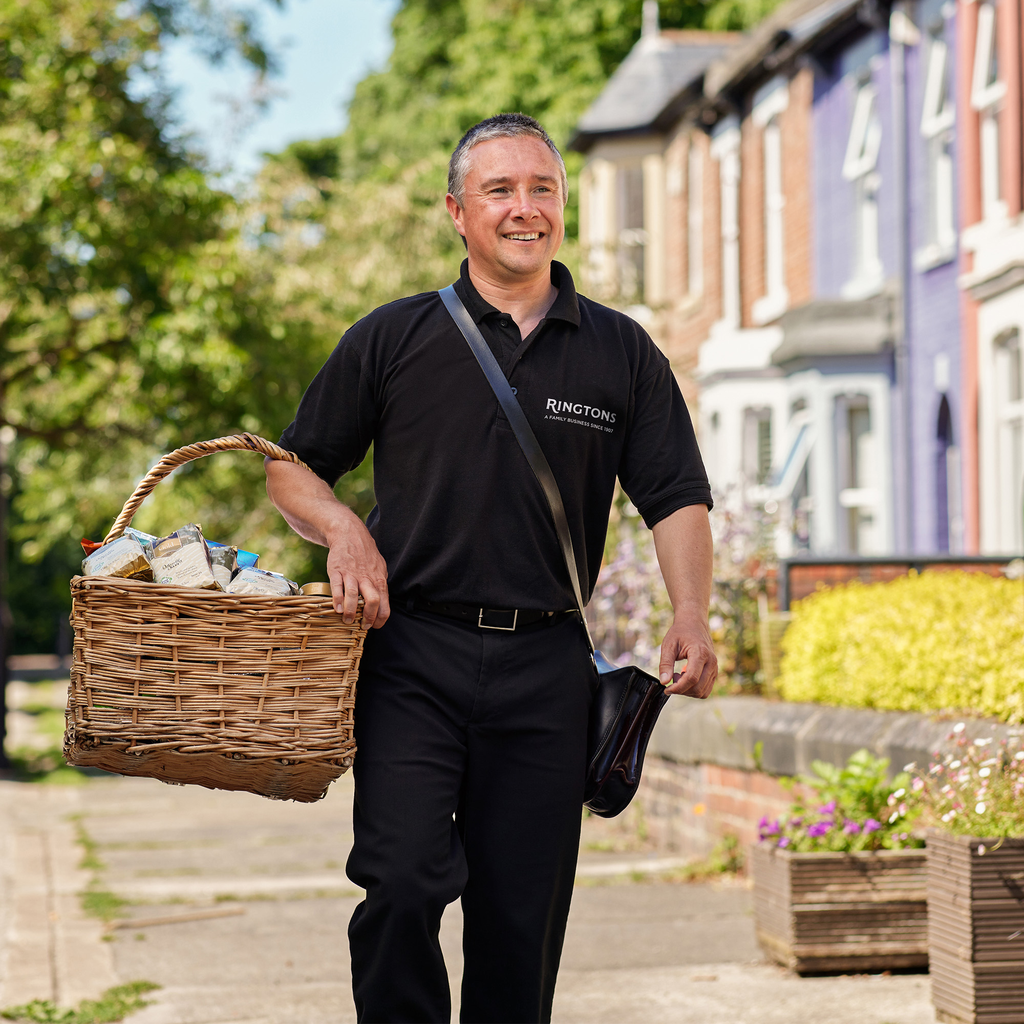 Person smiling carrying basket of food items down street.