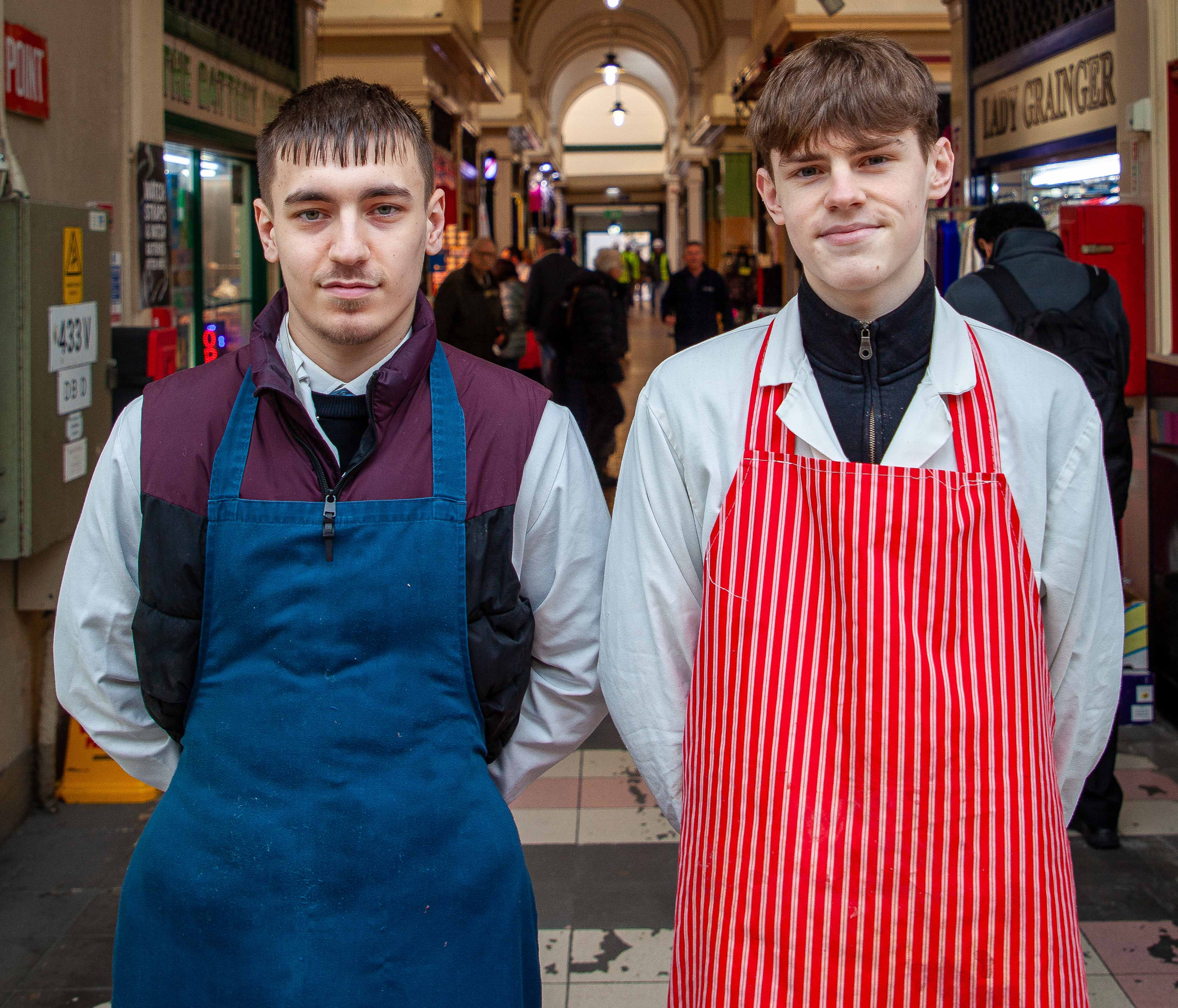 Two young men in work clothes in a busy setting
